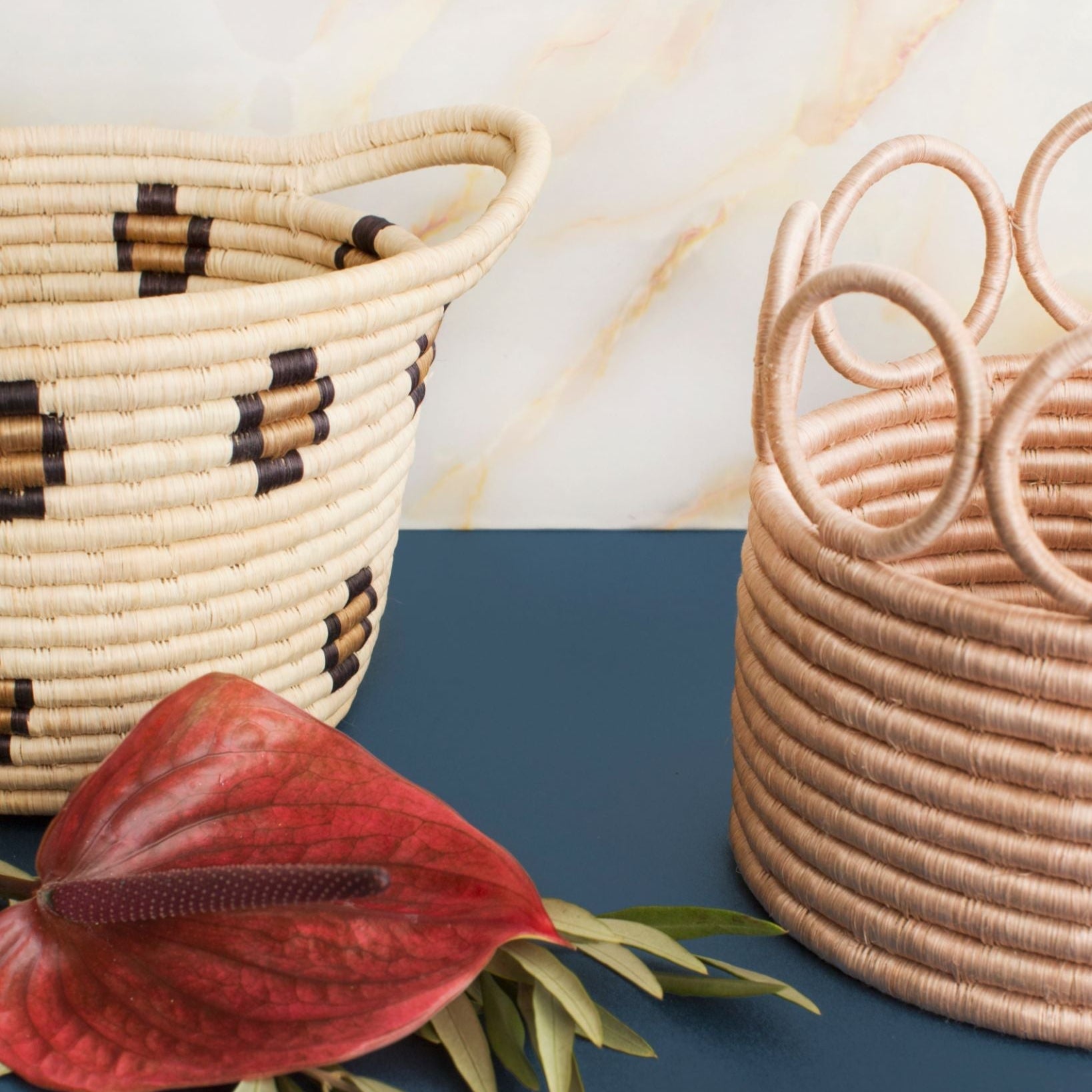 Two woven baskets and a red flower on a blue and beige background