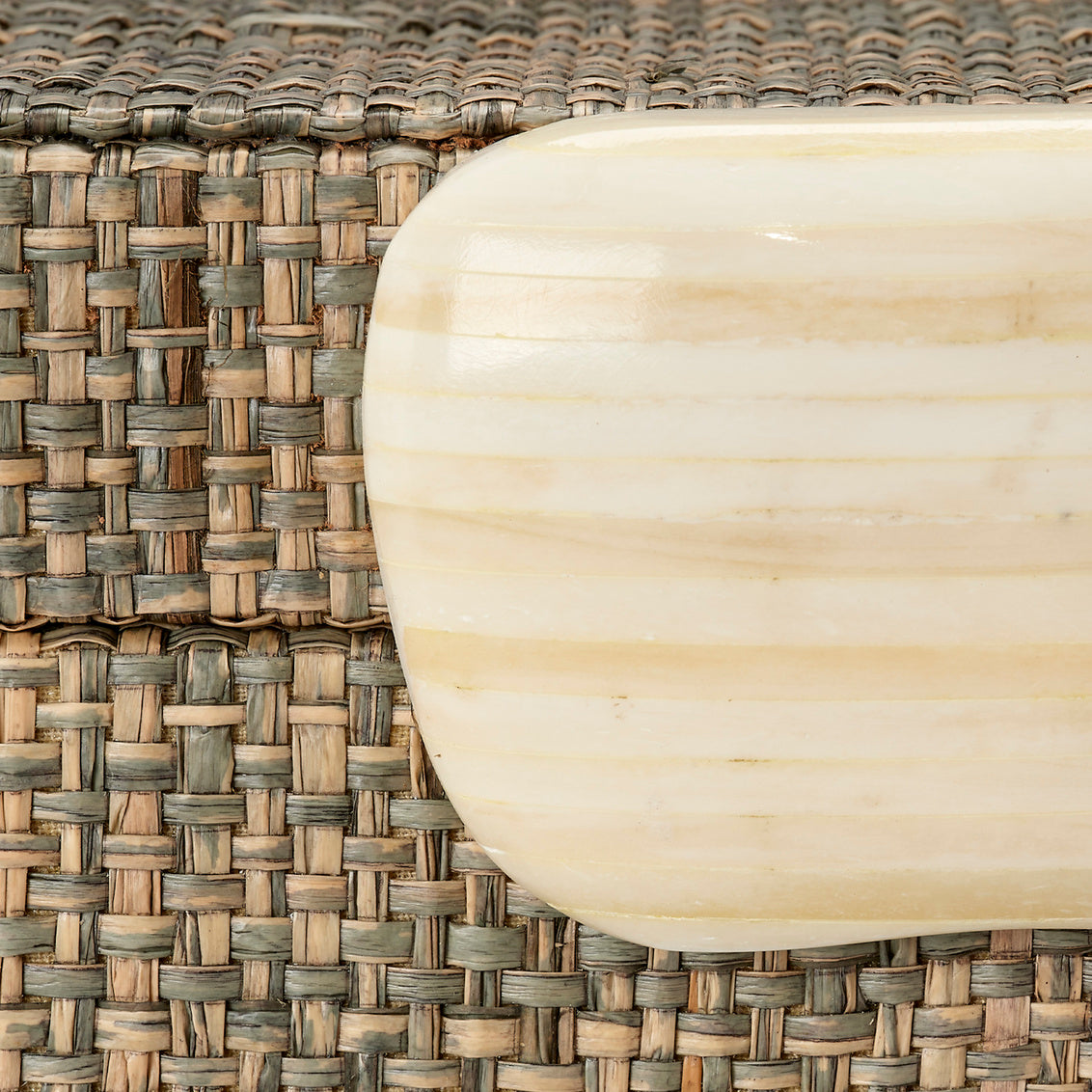 Woven storage box with a bone handle on a white background
