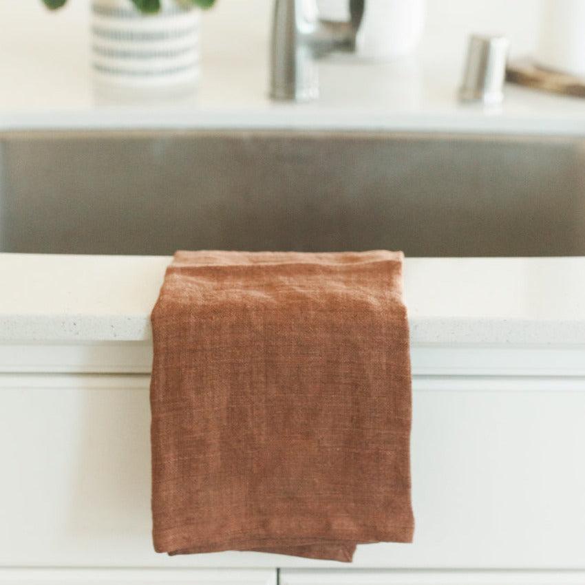 Brown towel hanging over sink with a blurred sink in the background