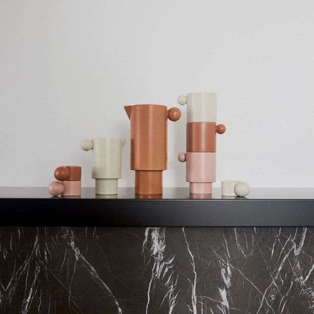 Set of colorful ceramic vases on a black marble surface with a white background