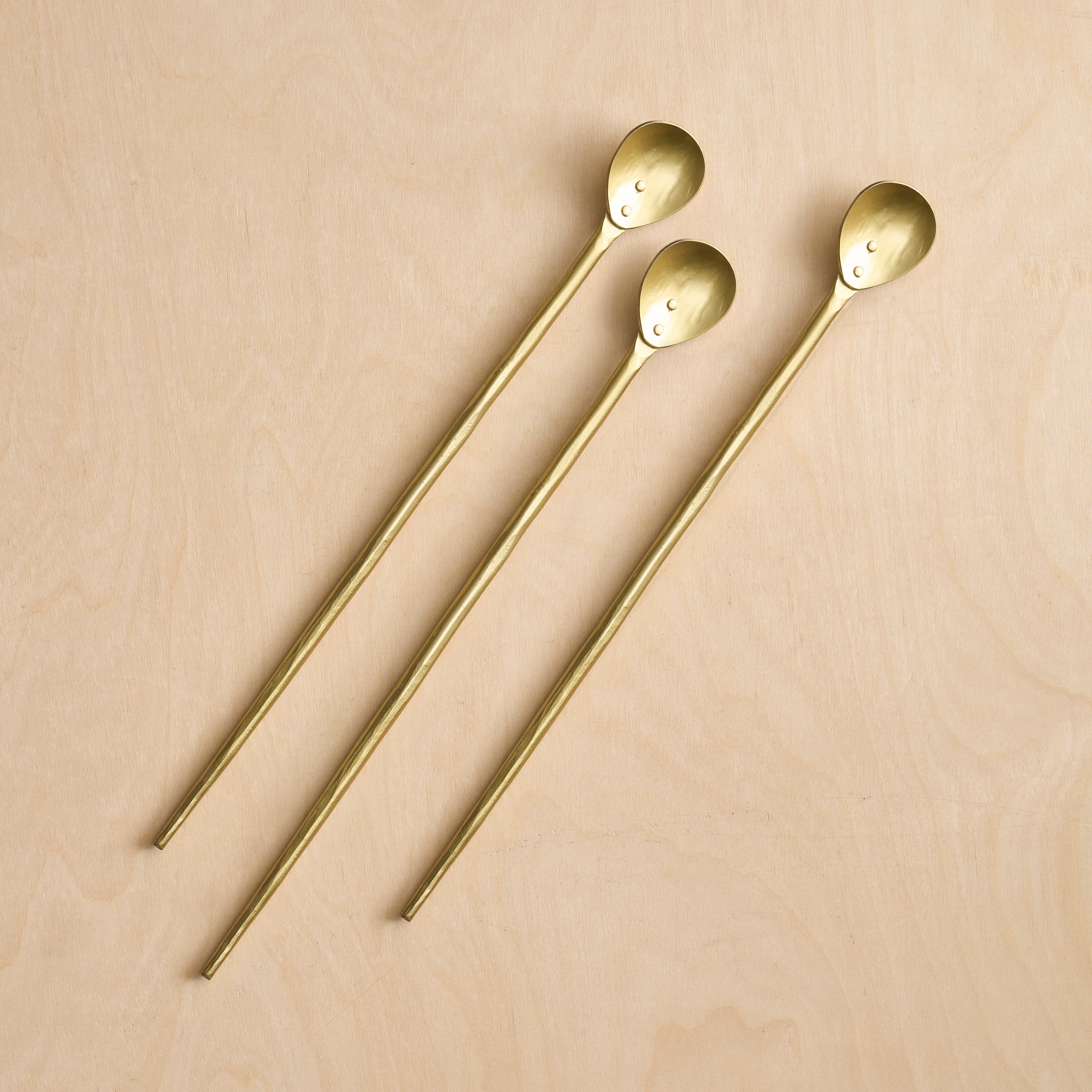 Three gold spoons on a beige background
