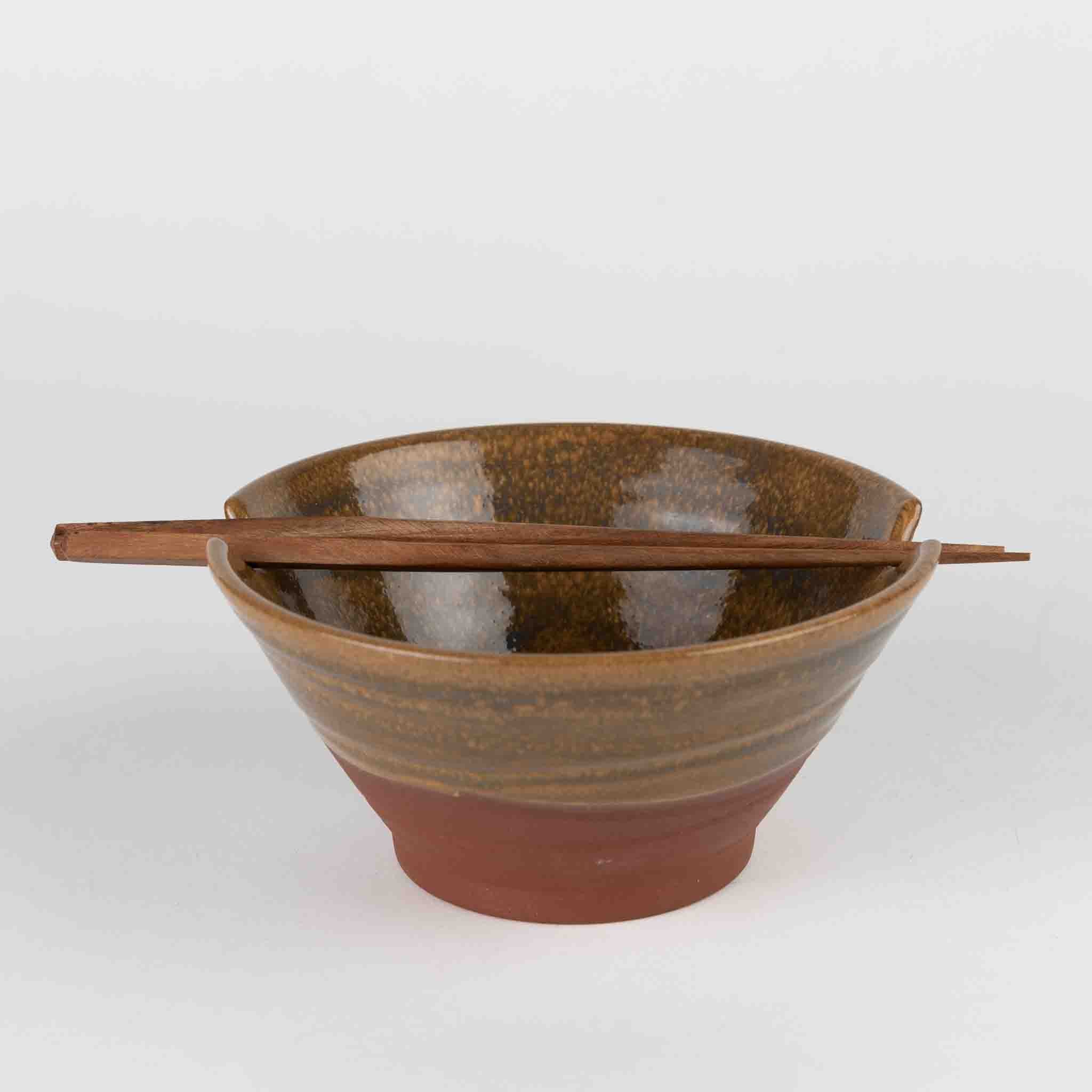 Brown ceramic bowl with wooden chopsticks on a white background