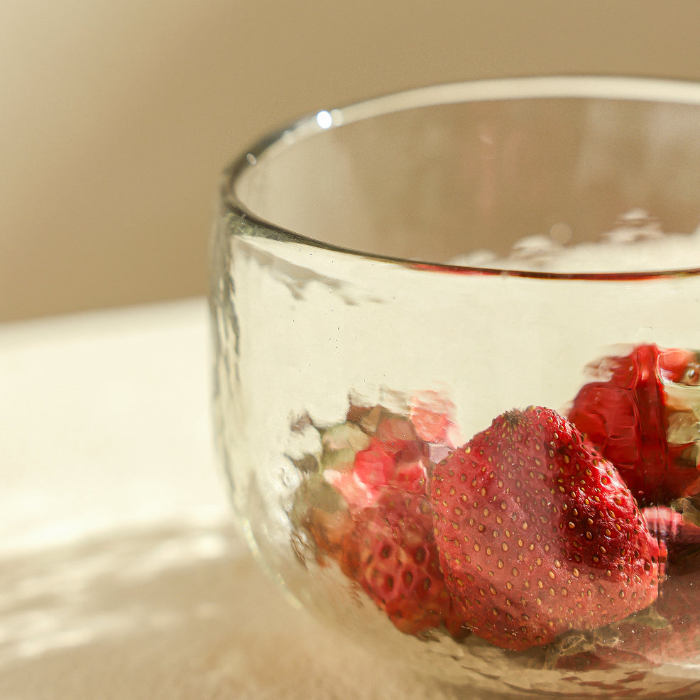 Clear glass bowl with strawberries on a beige background