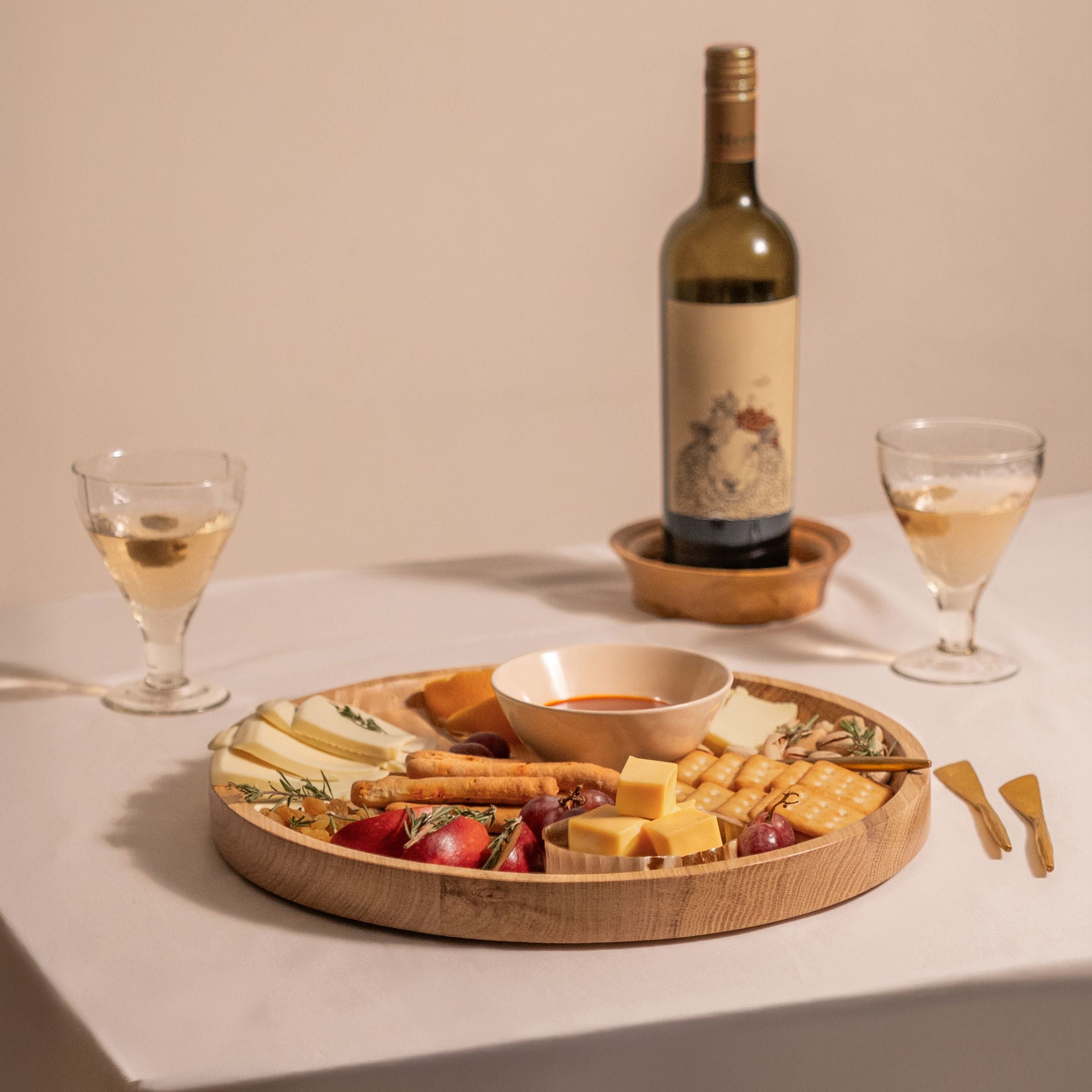Wine bottle with two glasses and a cheese plate on a beige background