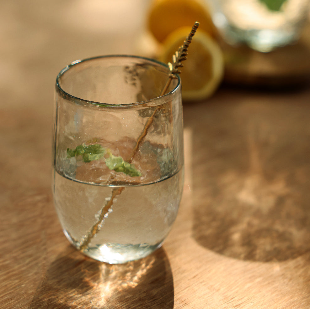 Clear glass with a lemon twist on a wooden surface