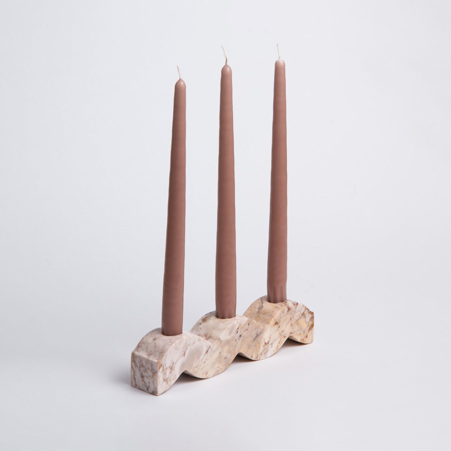 Candle holder with three mauve candles on a light gray background