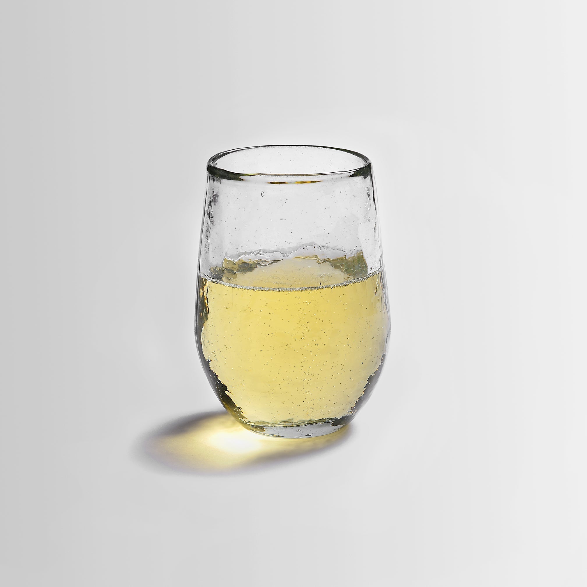 Clear pebbled glass with white liquid on a light gray background