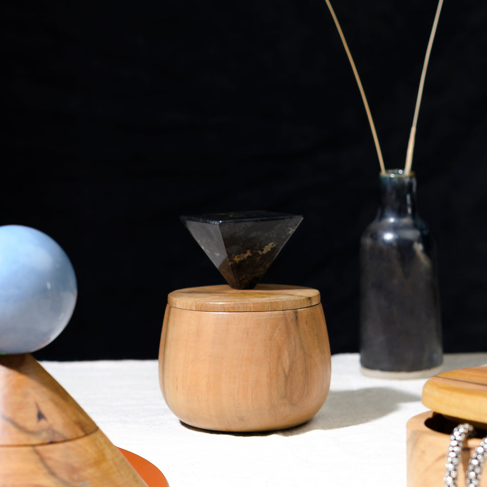 Wooden container with a geometric stone on top, set against a dark background.
