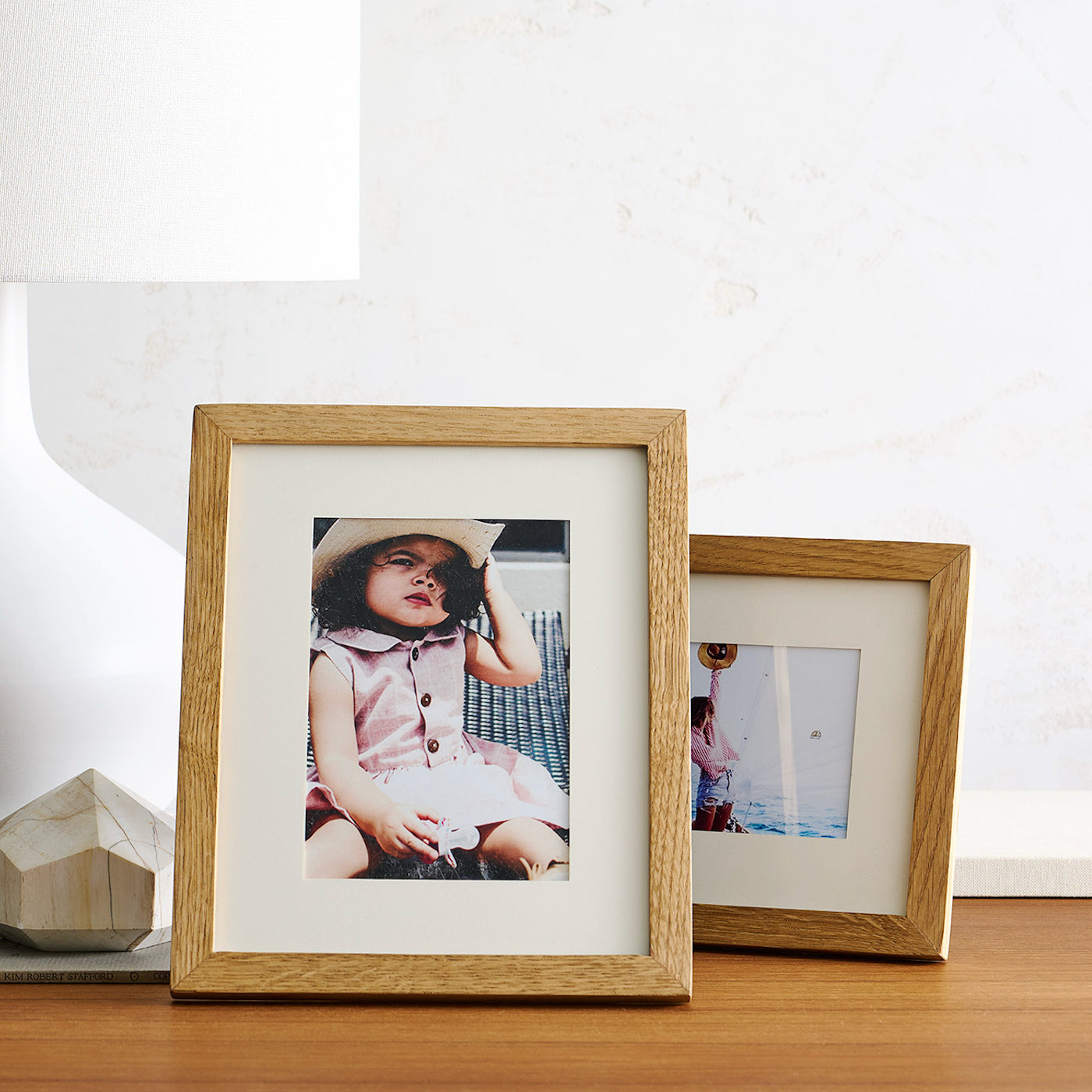 Two wooden picture frames on a wooden surface with photos inside.
