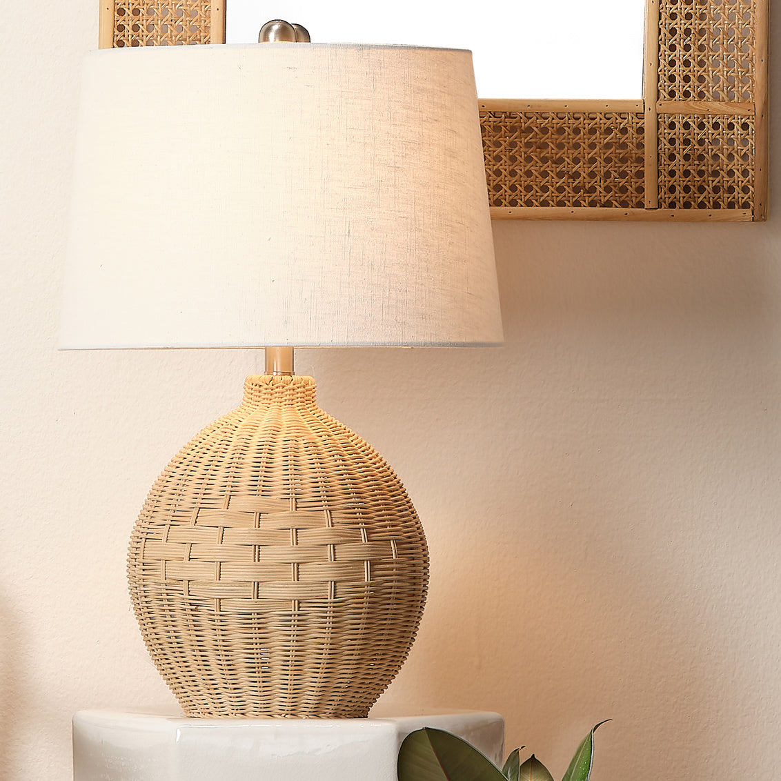 Woven rattan table lamp with a white shade on a neutral background