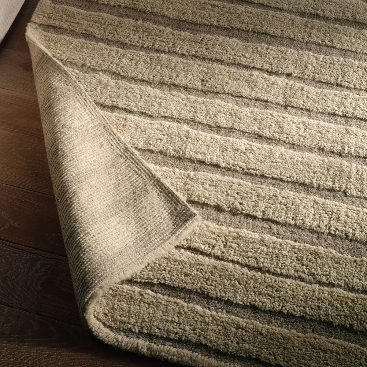 Textured beige rug on a wooden floor