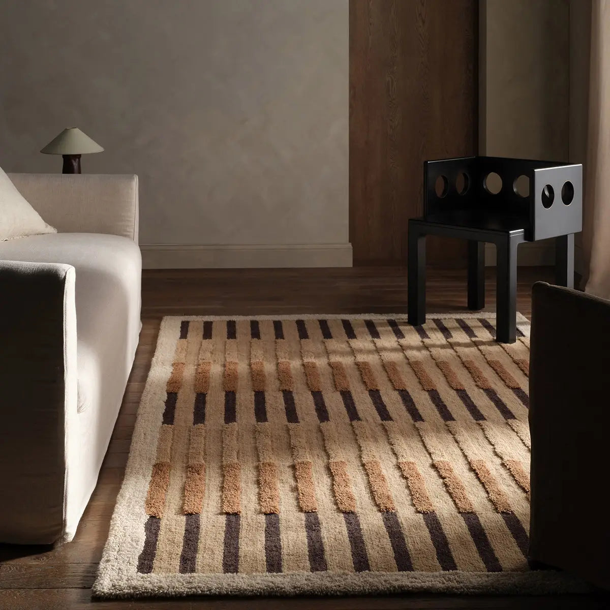 Living room with a patterned rug, white sofa, and black chair.
