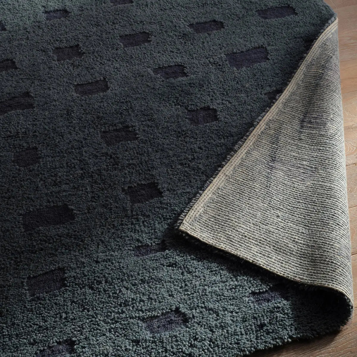 Close-up of a textured blue rug with a geometric pattern on a wooden floor.