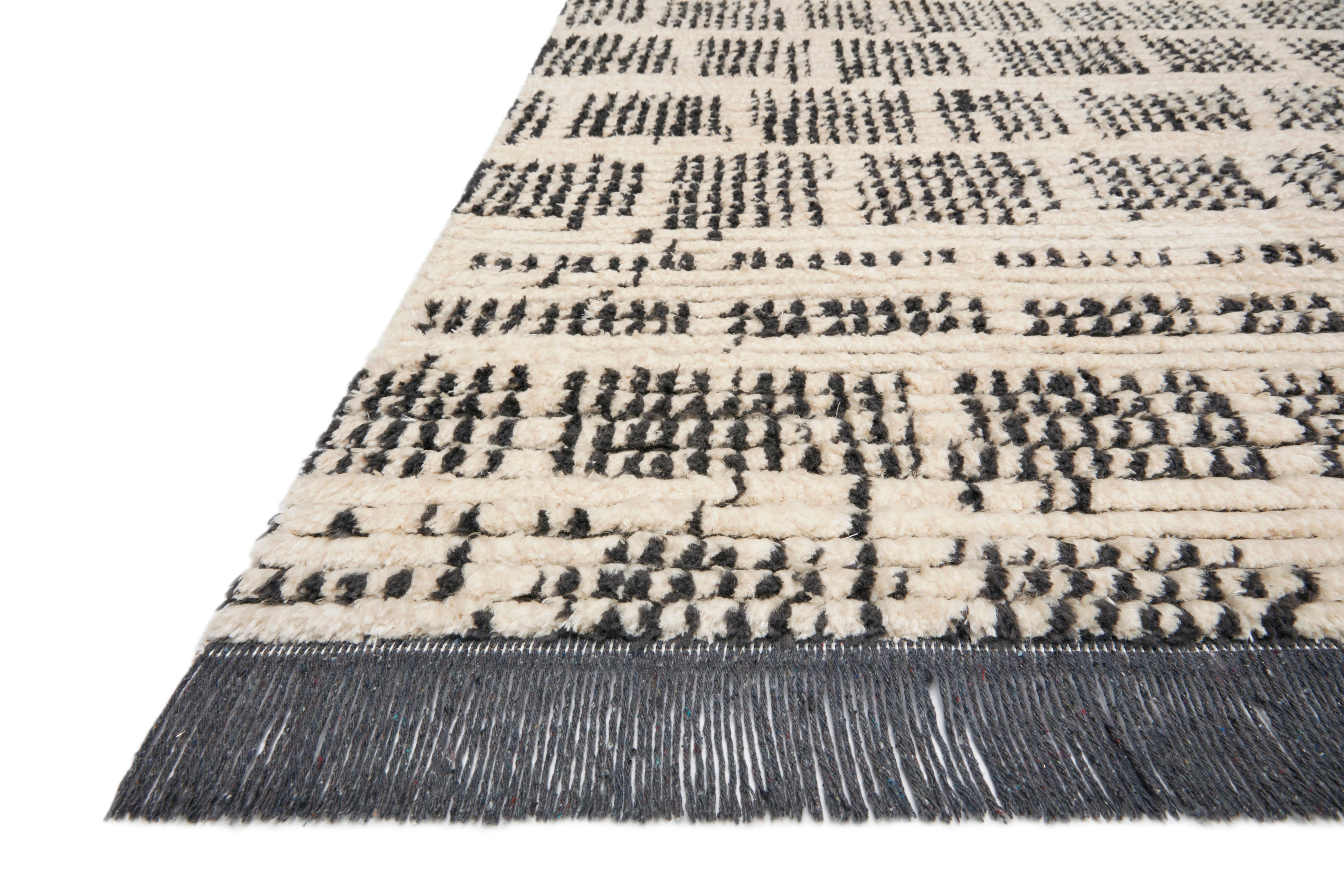 A rectangular rug with a geometric pattern featuring a combination of black and gray colors, with subtle fringes on the edges.