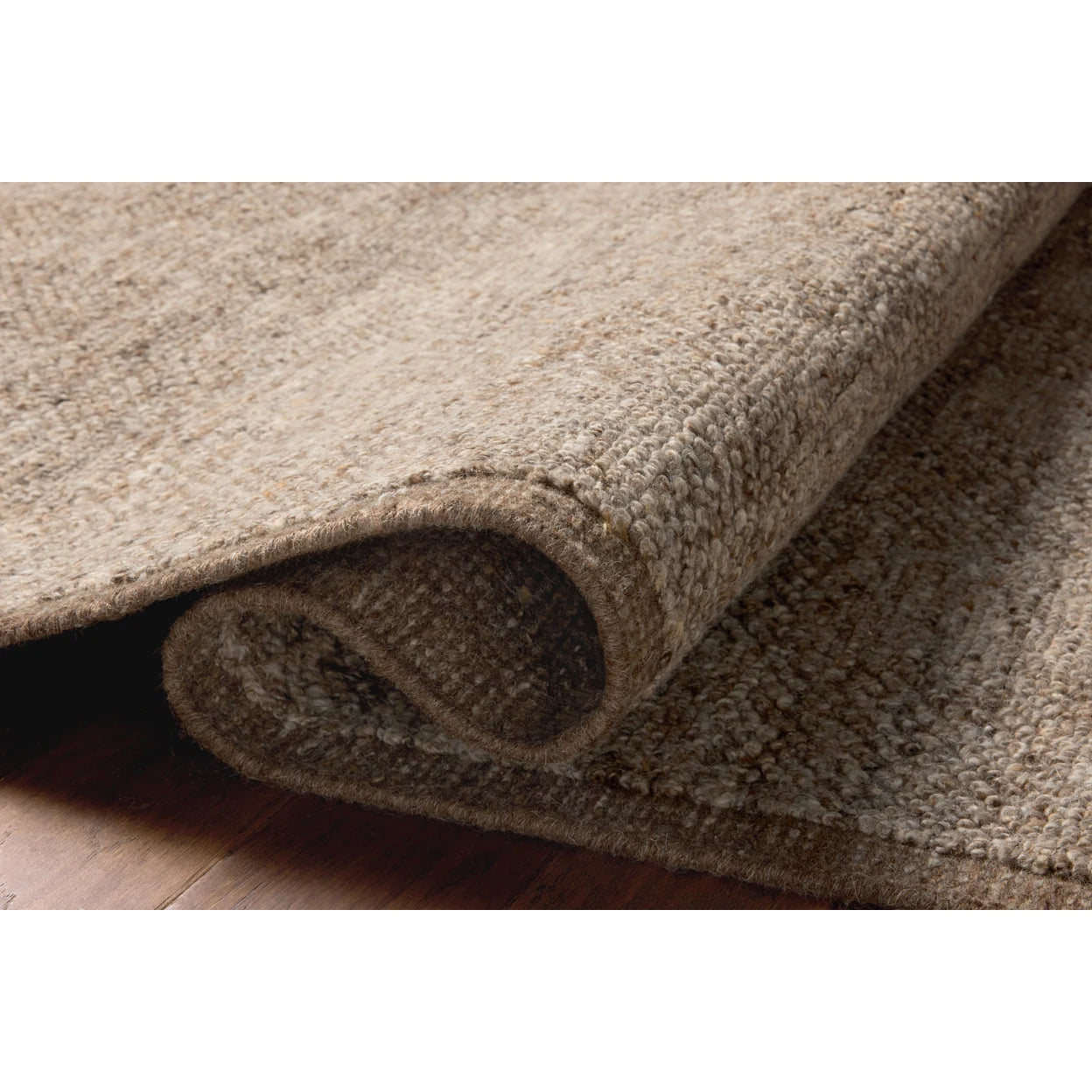 Close-up of a beige carpet roll on a wooden floor