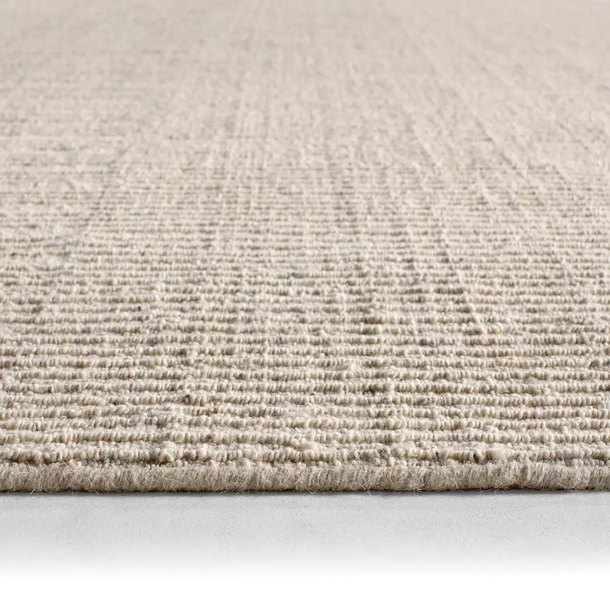 Close-up of a textured beige carpet on a light gray background
