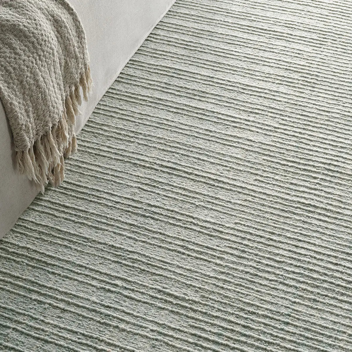 Textured rug with a corner of a blanket on a light background