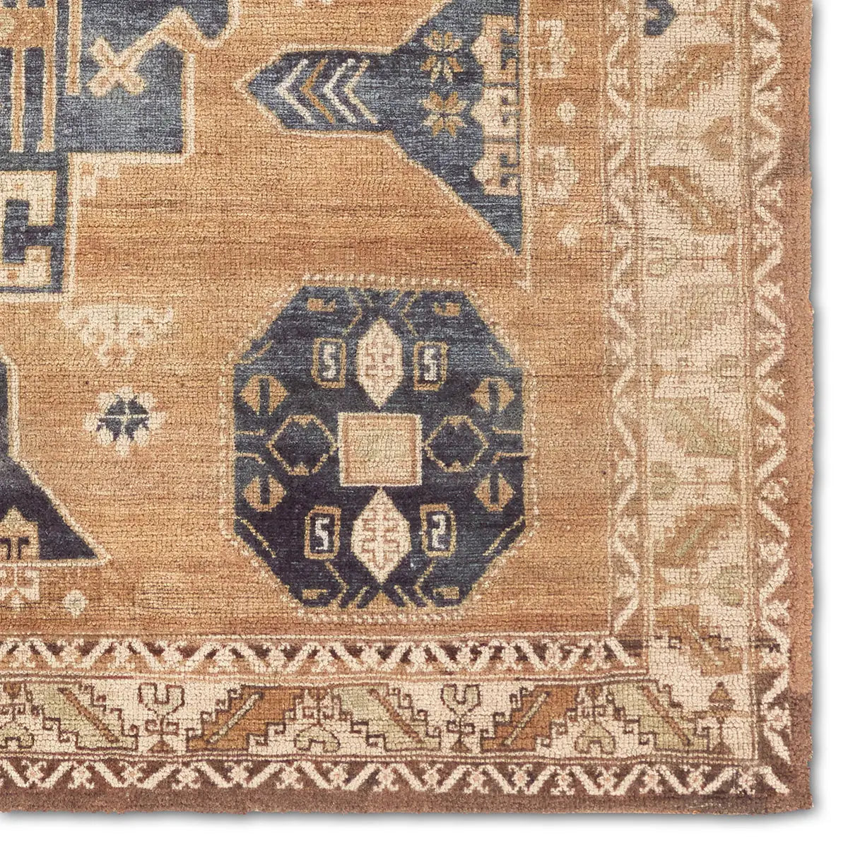 Close-up of a patterned rug with geometric designs in blue, brown, and beige.