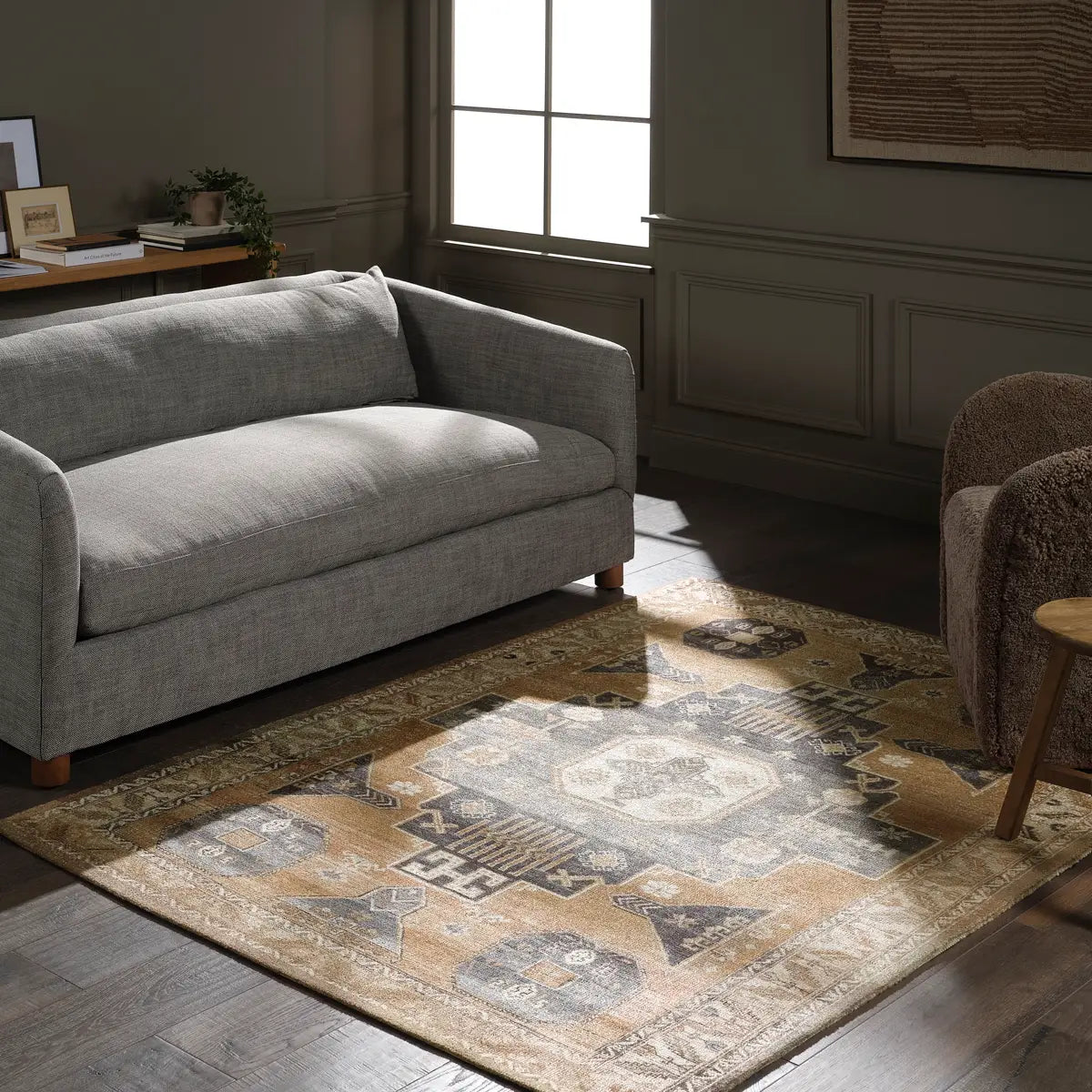 Gray sofa in a living room with a patterned rug and armchair.