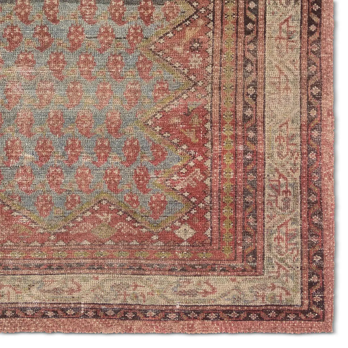 Close-up of a patterned rug corner with red and beige colors