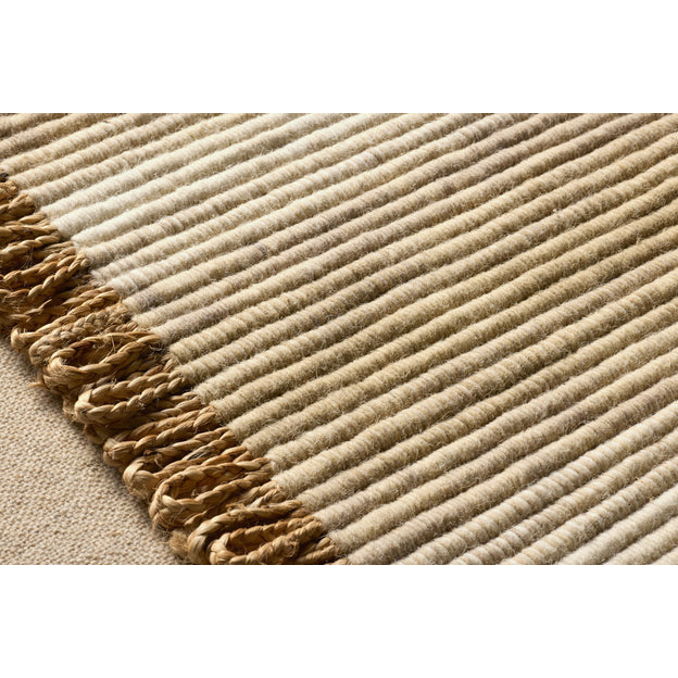 Close-up of a textured beige rug with a fringed edge.