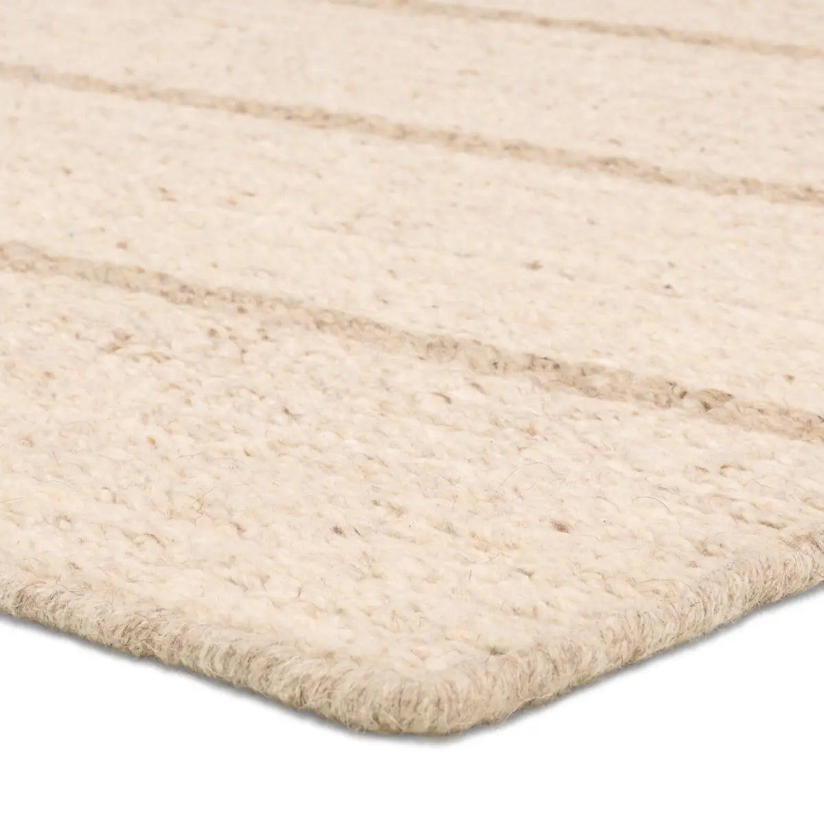 Close-up of a beige woven rug with a textured pattern on a white background