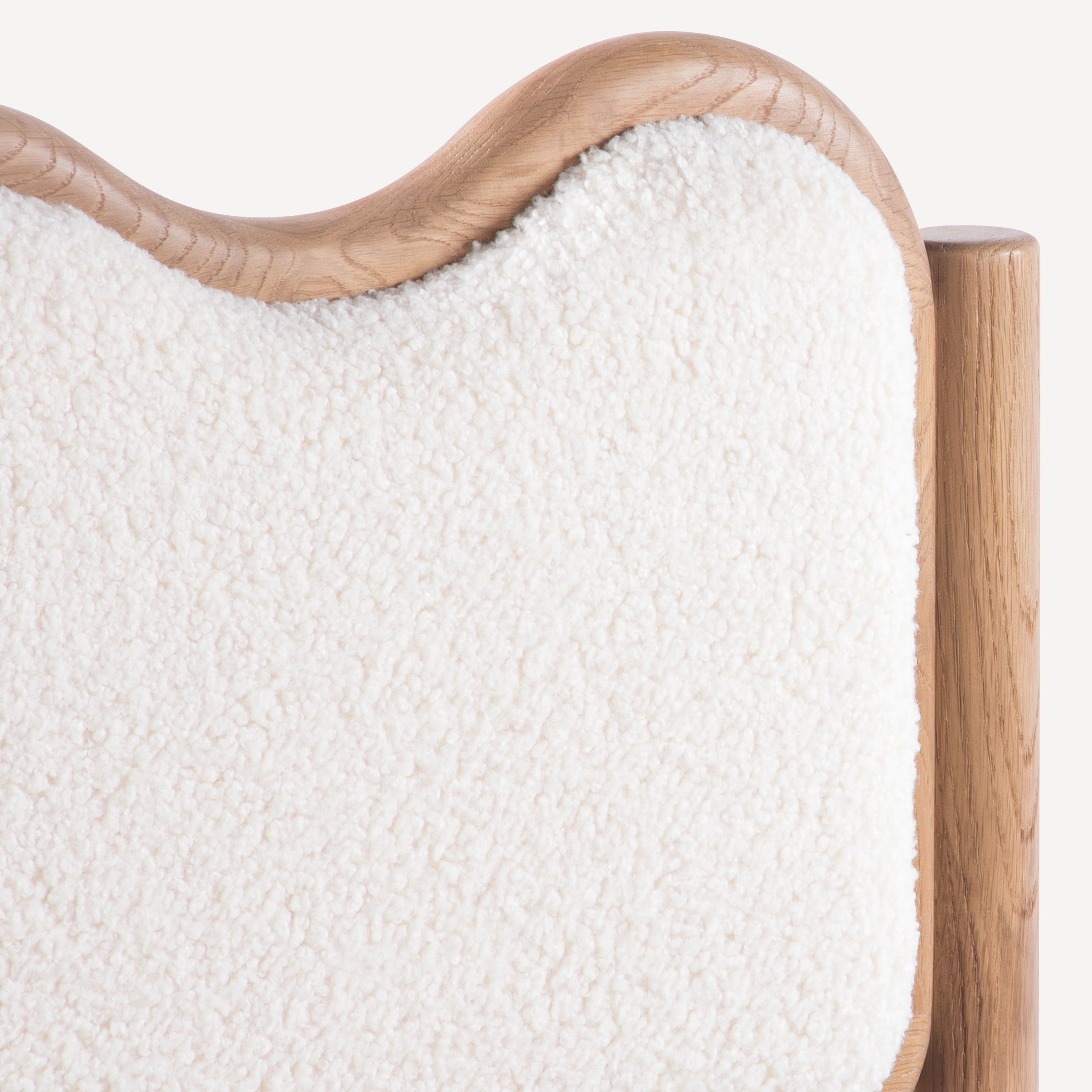 Close-up of a cream-colored textured bouclé upholstered headboard with a natural light oak wood frame on a clean white background.
