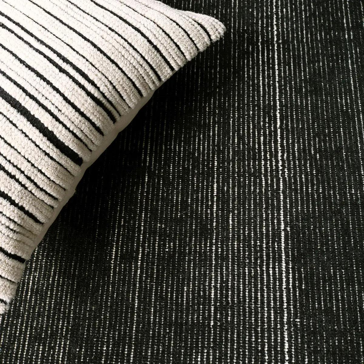 Textured black and white fabric with a striped pillow on top