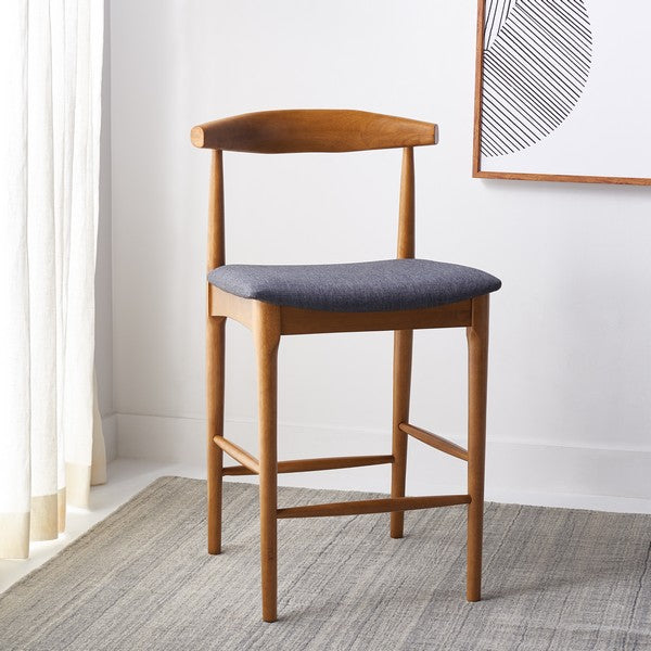 Wooden bar stool with a gray cushioned seat in a room setting.