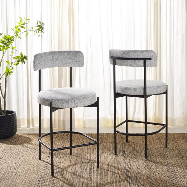 Two gray cushioned bar stools with black metal frames on a carpeted floor.