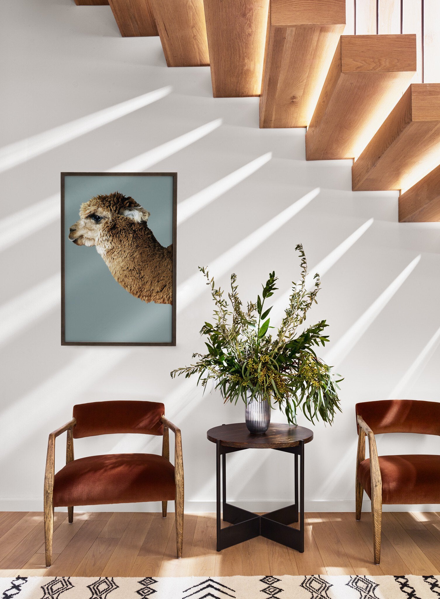 Staircase with wooden steps, framed animal print, and decorative table with flowers.