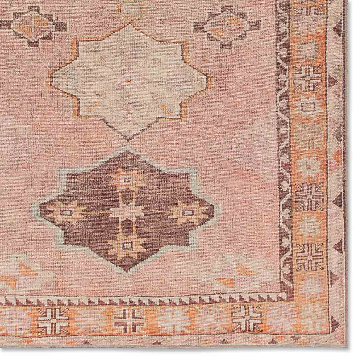 Close-up of a patterned rug with geometric designs on a pink background