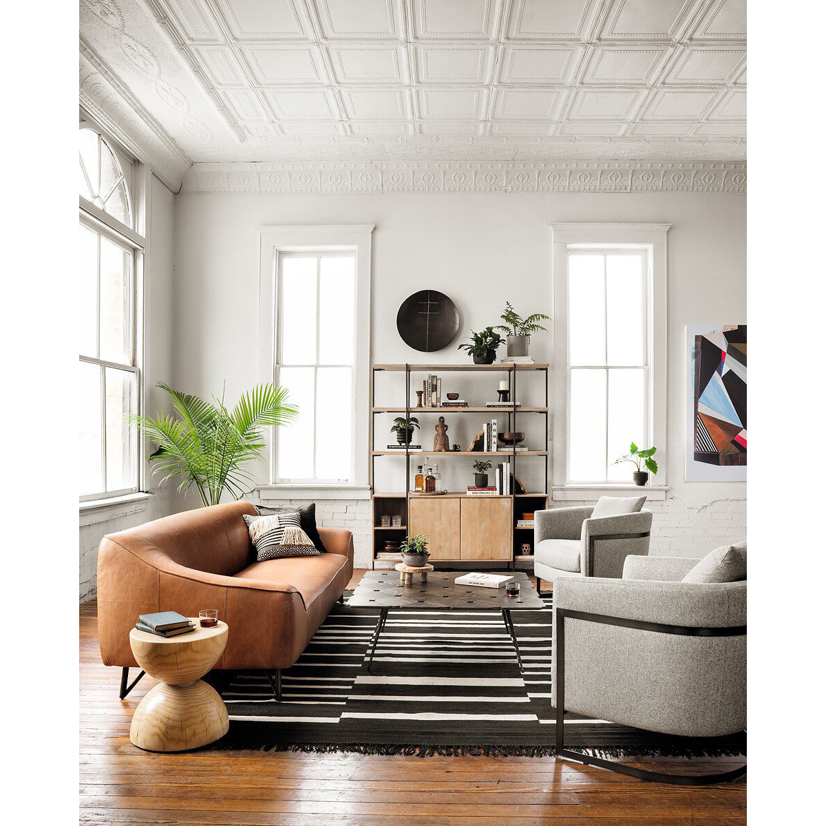 Modern living room with a brown sofa, pine coffee table, and bookshelf.