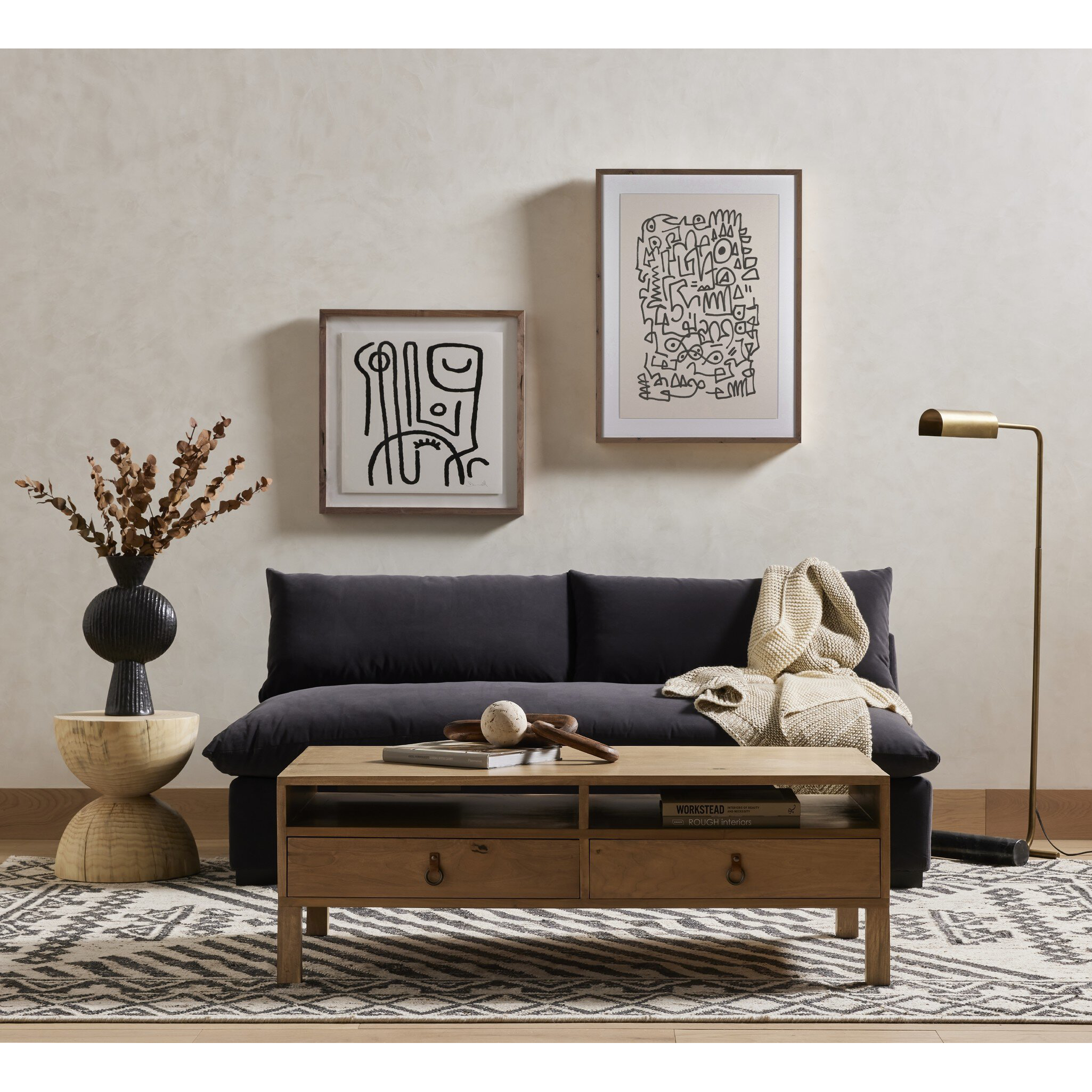 Modern living room with a black sofa, wooden coffee table, and framed artwork on the wall.