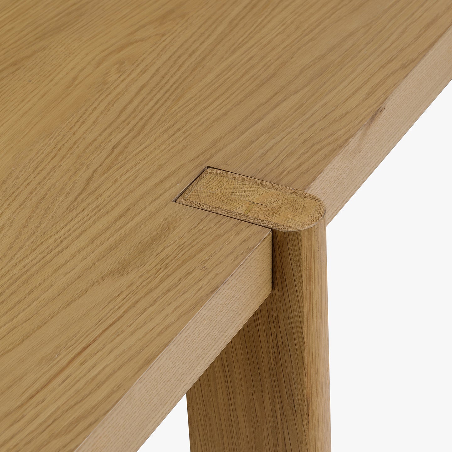Close-up of a wooden table corner with a visible brand logo.