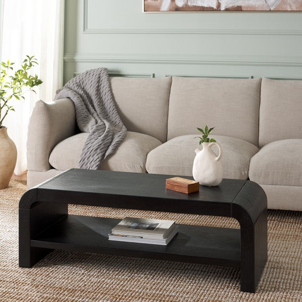 Black coffee table in front of a beige sofa with decorative items