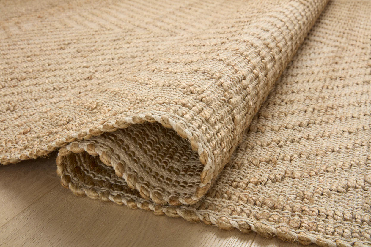 Rolled beige jute rug on a wooden floor