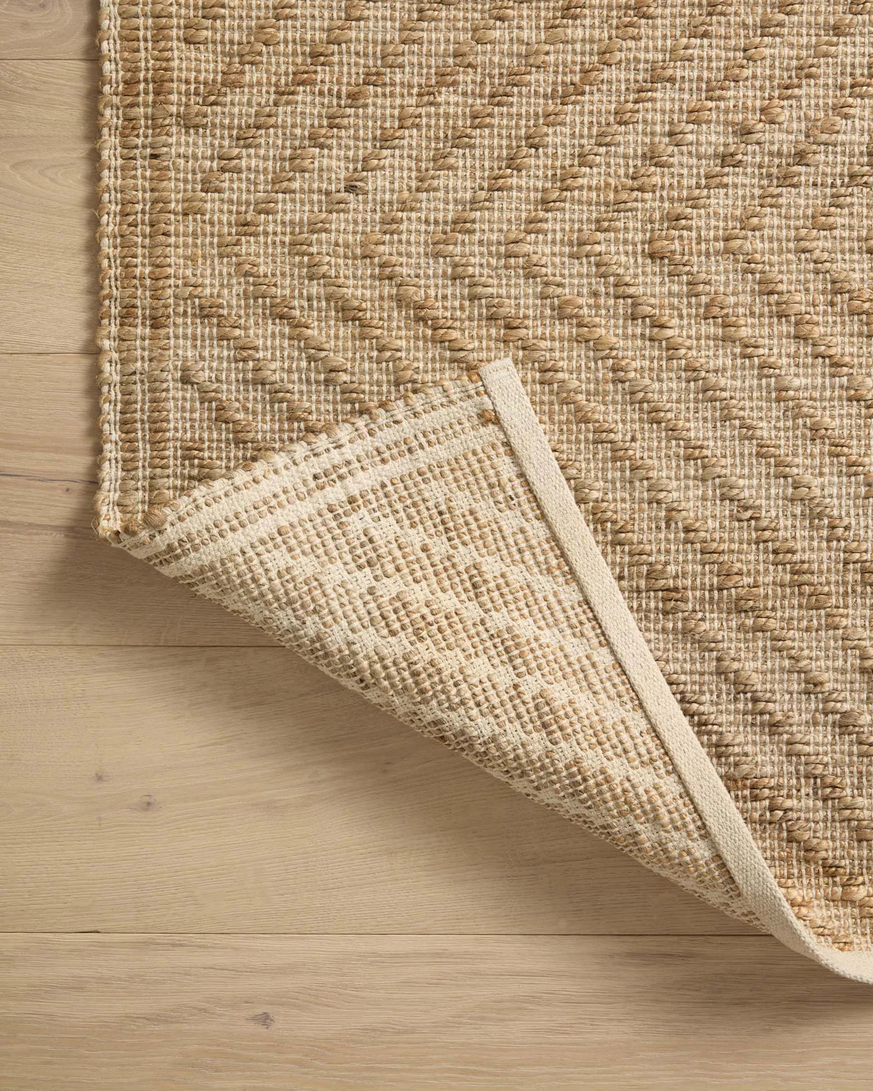 Close-up of a woven beige rug on a wooden floor