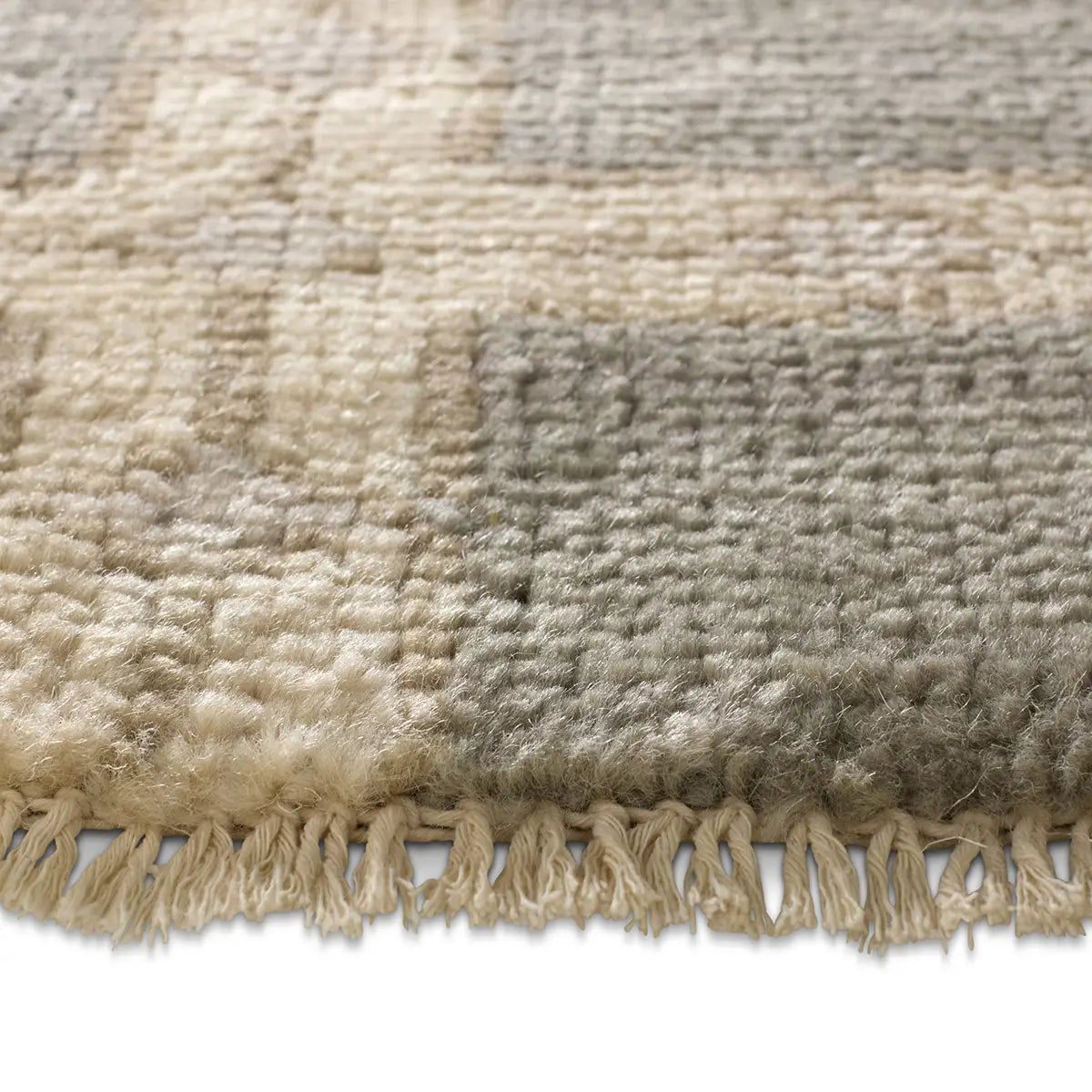Close-up of a textured rug with fringes on a white background