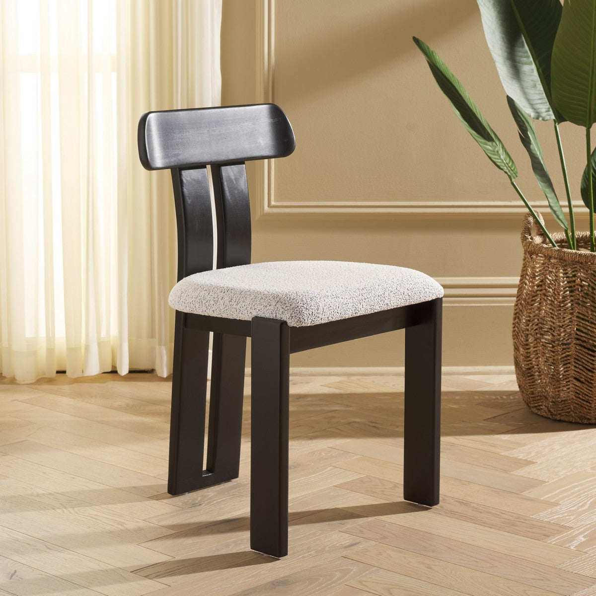 Black chair with a patterned cushion on a wooden floor, next to a plant.