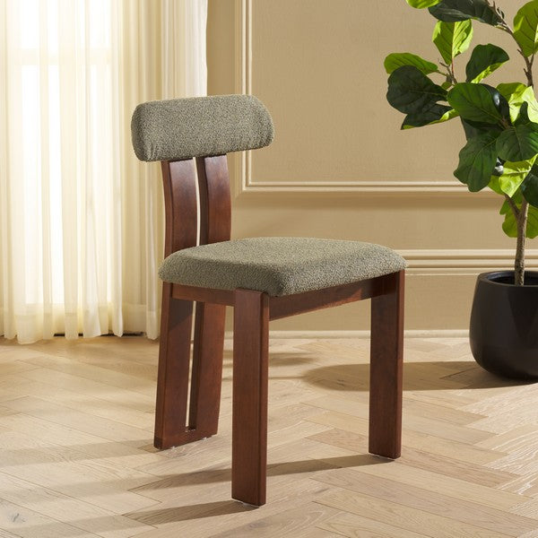 Wooden chair with green cushioned seat and backrest in a room with curtains and a plant.
