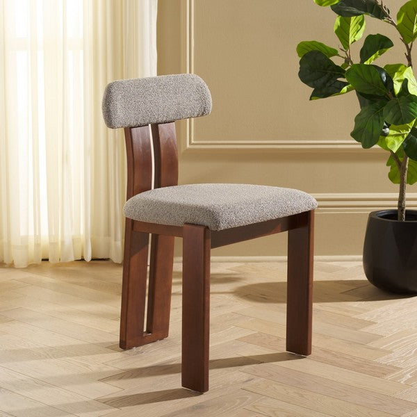 Chair with wooden frame and gray cushioned seat in a room with a plant and curtains.