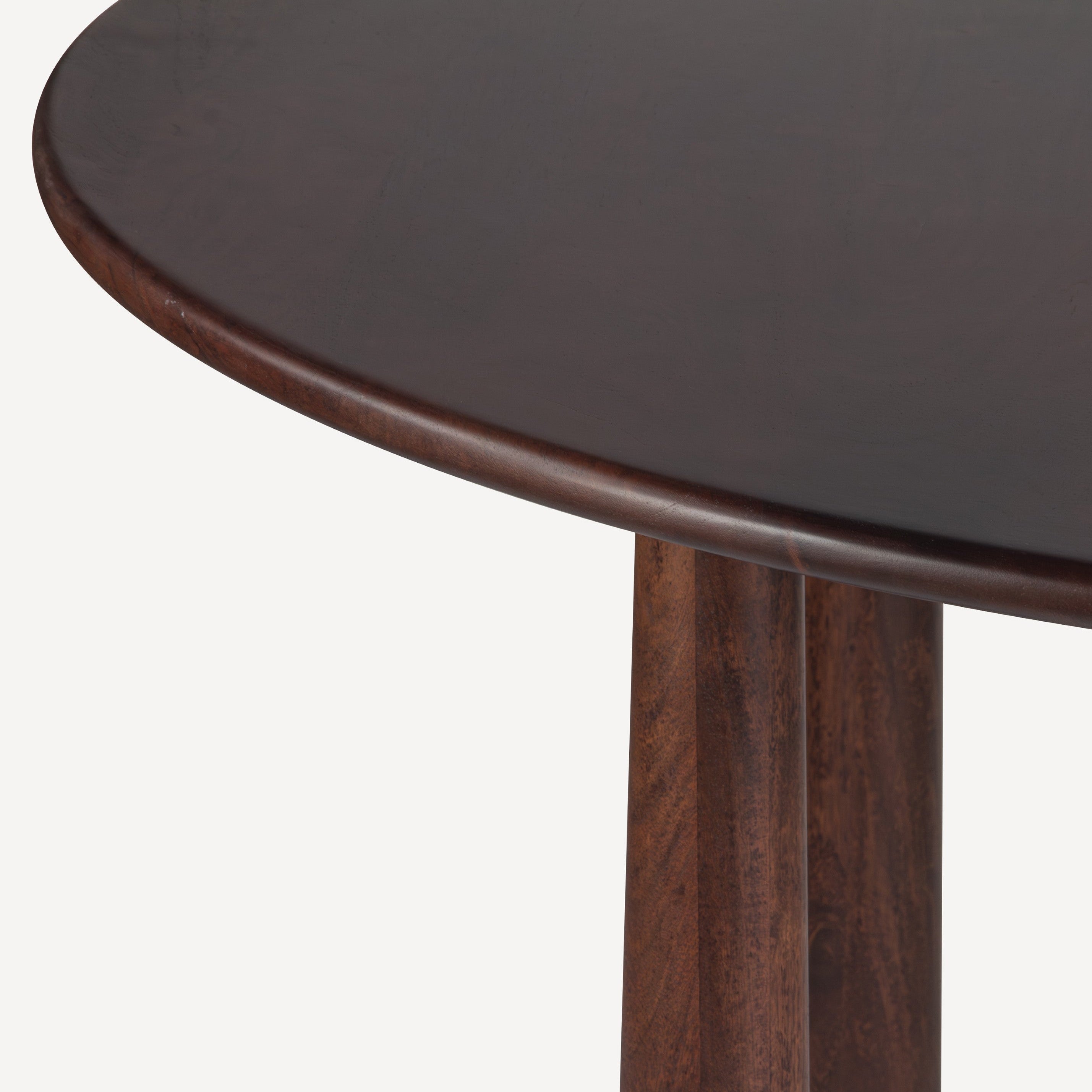 Close-up of a dark brown wooden dining table showing the curved tabletop edge and part of the pedestal base against a light gray background.