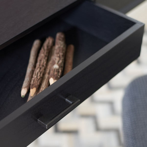 Black fire pit with logs inside, blurred outdoor background