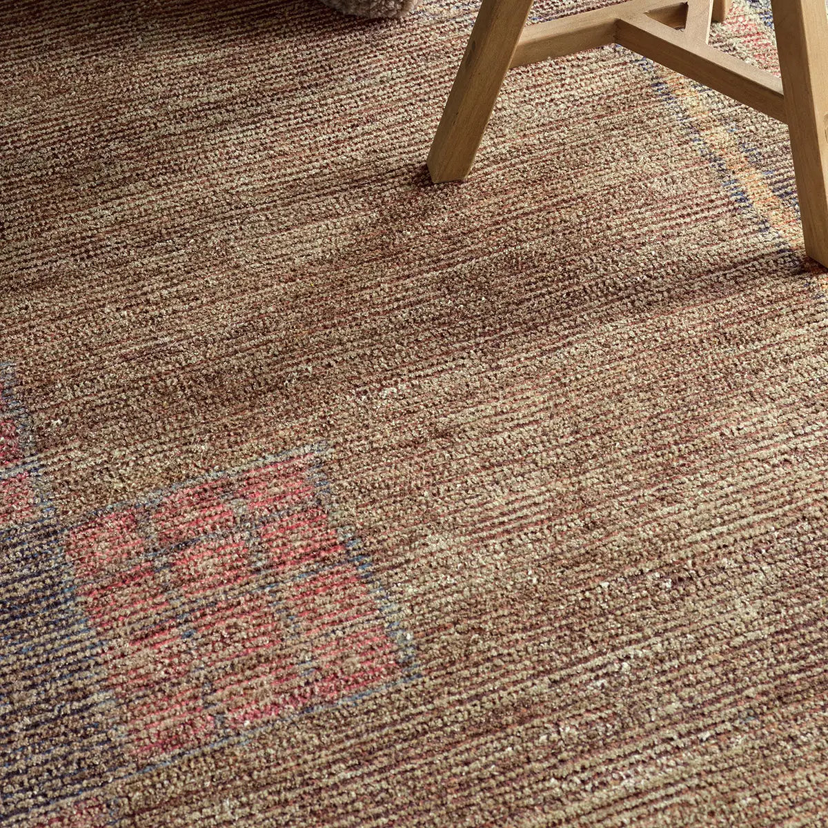 Textured brown carpet with a chair leg partially visible
