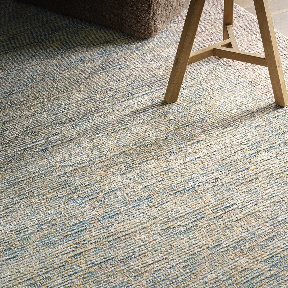 Textured blue and beige rug with a wooden chair leg in the foreground