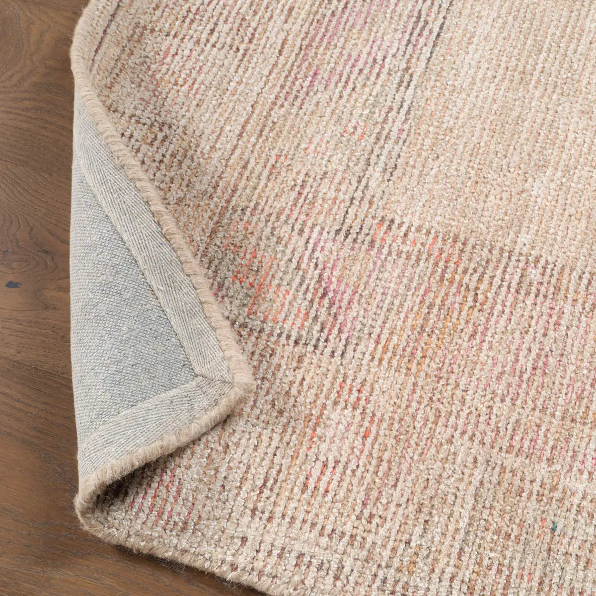 Close-up of a textured rug corner on a wooden floor