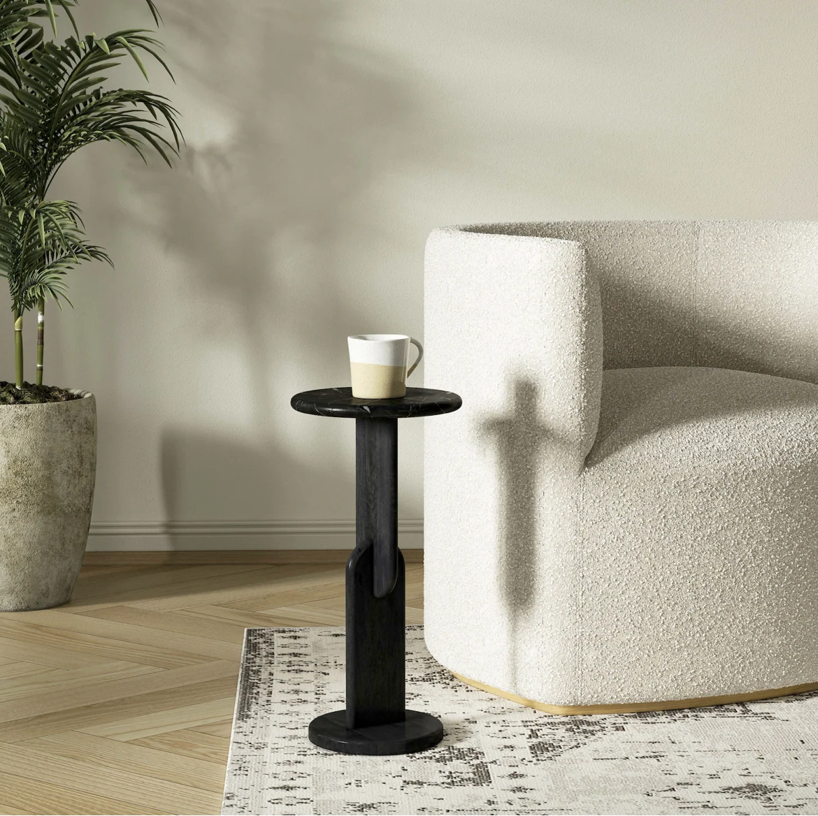 Black side table with a white mug next to a white armchair in a room with a plant and wooden floor.