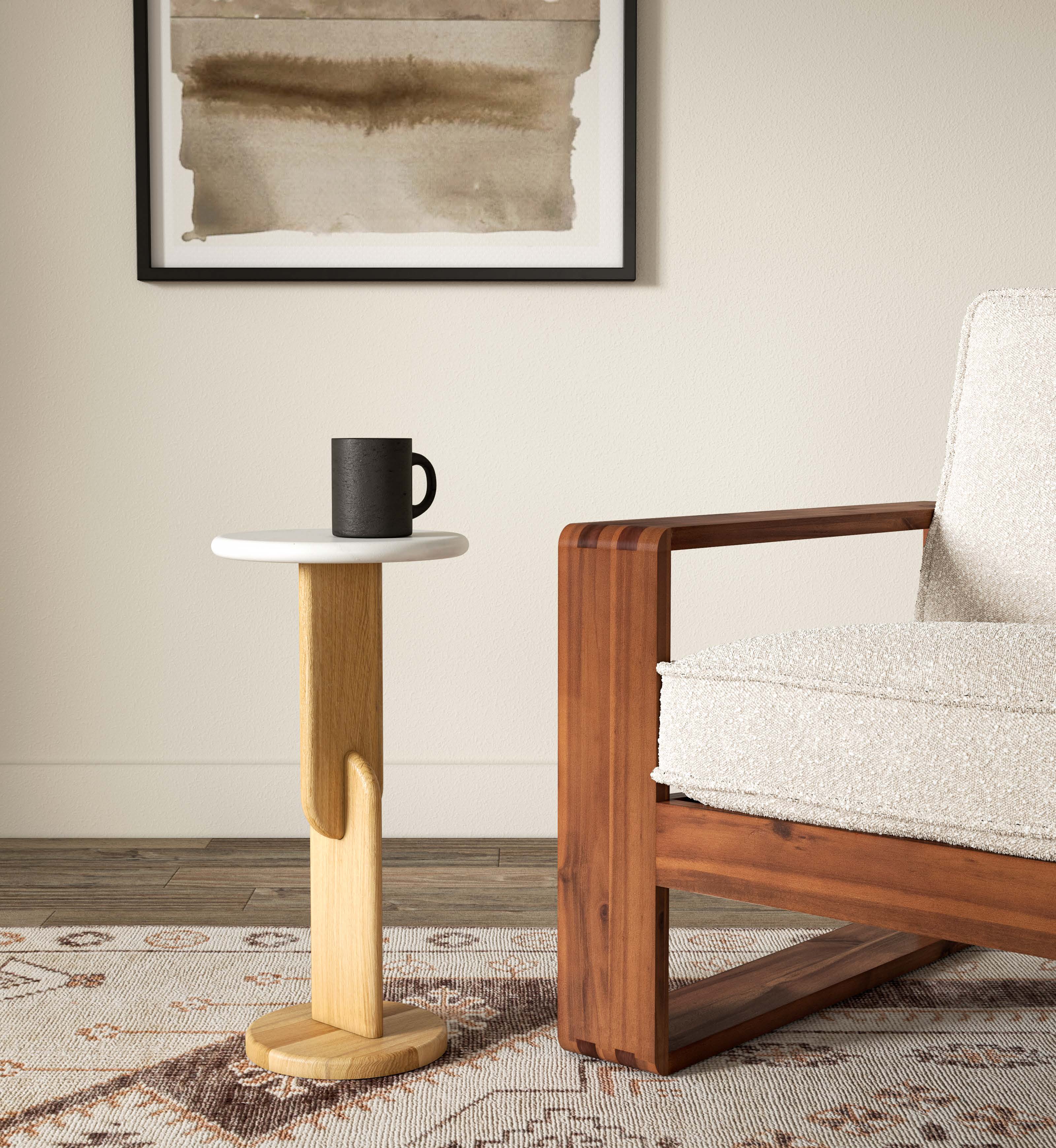 Small wooden side table with a white top next to a wooden armchair in a living room setting.