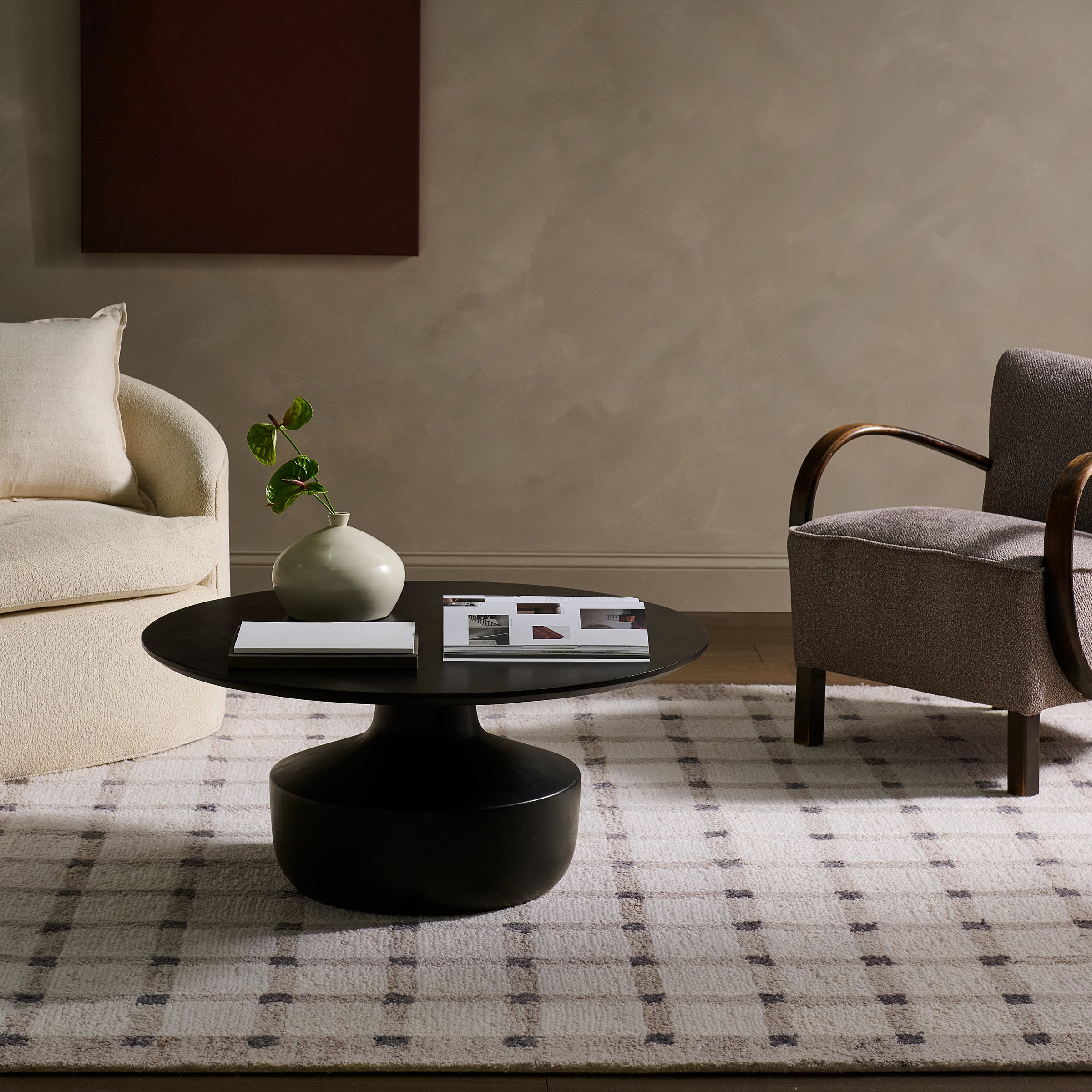 Modern living room with a black round table, gray armchair, and beige sofa.